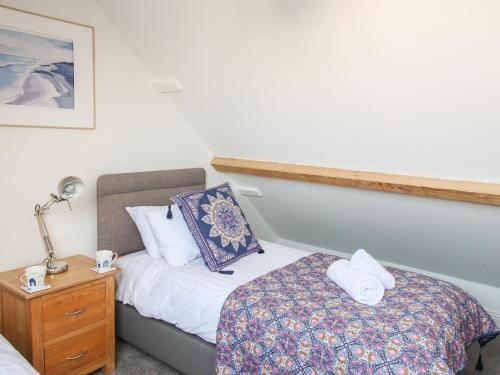 a small bedroom with a bed and a nightstand with towels at Swanage Driftwood in Swanage