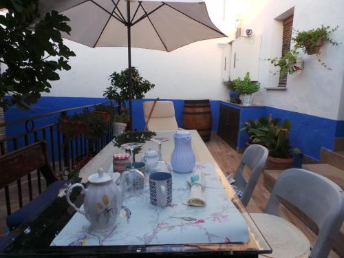 a table with a tea set on it with an umbrella at Apts la cañada birding con encanto y patio en monfrague torrejon el Rubio in Torrejón el Rubio