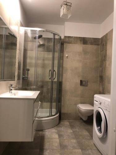 a bathroom with a shower sink and a washing machine at Apartament Przy Lesie in Międzywodzie