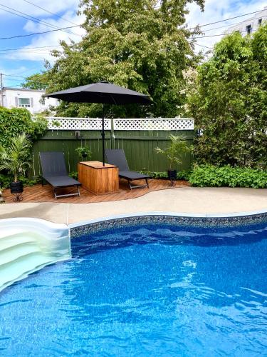 a pool with a table and an umbrella and chairs at La Villa du Notaire in Lévis