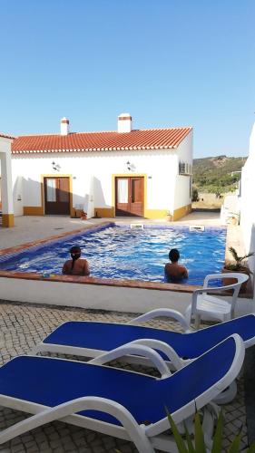 two men are sitting in a swimming pool at Carrapateiramar Guest House in Carrapateira