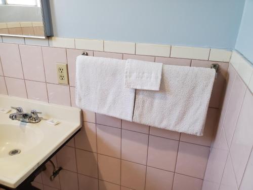 baño con lavabo y toallas colgadas en la pared en Rose motel, en Compton