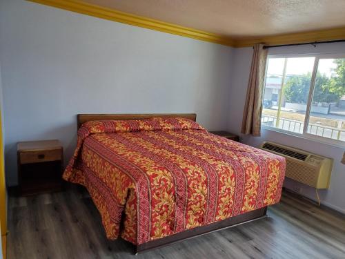 a bedroom with a bed with a red comforter and a window at Rose motel in Compton