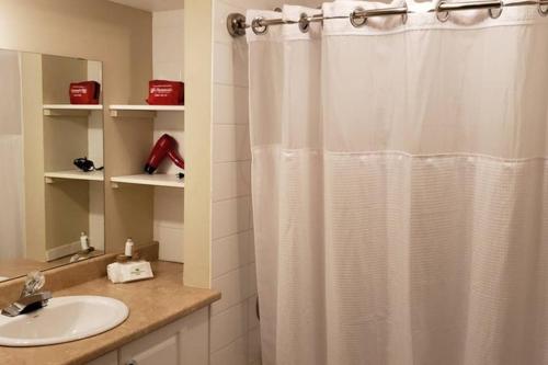 a bathroom with a white shower curtain and a sink at 2-Bedroom Apartment Sweet #2 by Amazing Property Rentals in Gatineau