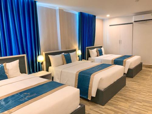 - 2 lits dans une chambre d'hôtel dotée de rideaux bleus dans l'établissement LION HOTEL, à Cần Thơ