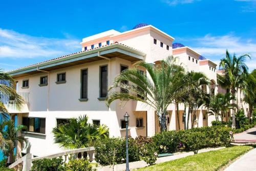 a large white building with palm trees in front of it at Beautiful Condo in Peaceful Cliffside Location with a Private Balcony & Stunning Ocean and Mountain Views in Playa Flamingo