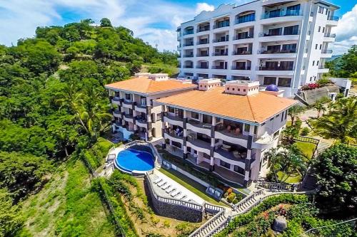 an aerial view of a building with a swimming pool at Beautiful Condo in Peaceful Cliffside Location with a Private Balcony & Stunning Ocean and Mountain Views in Playa Flamingo