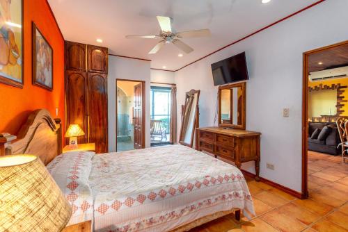 a bedroom with a bed and a dresser and a television at Warm Interiors and Orange Hues on Ground Floor in Front of Beach in Playa Flamingo