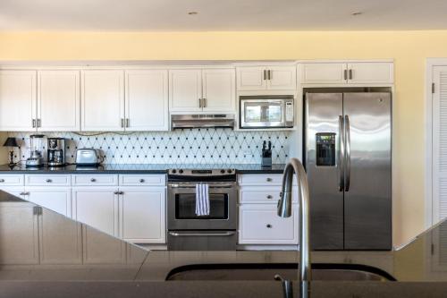 a kitchen with white cabinets and a stainless steel refrigerator at Luxury Flamingo home with ocean view sleeps 10 - walking distance from beach in Playa Flamingo