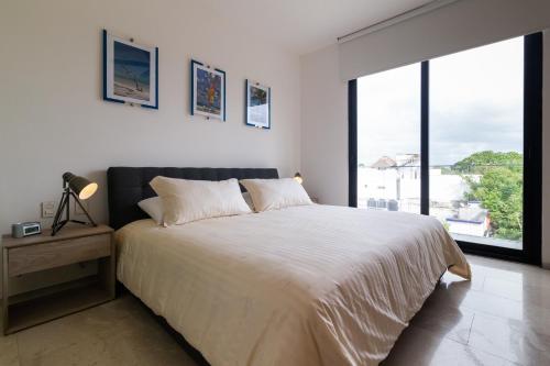 1 dormitorio con cama grande y ventana grande en Xaha Condo, en Playa del Carmen