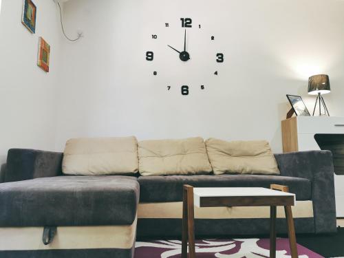 a living room with a couch and a clock on the wall at Cozy Corner Apartments - Free parking & Wi-fi in Ćuprija