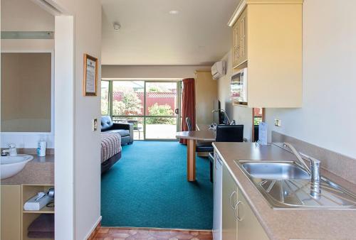a kitchen with a sink and a living room at ASURE Ashley Motor Lodge in Timaru