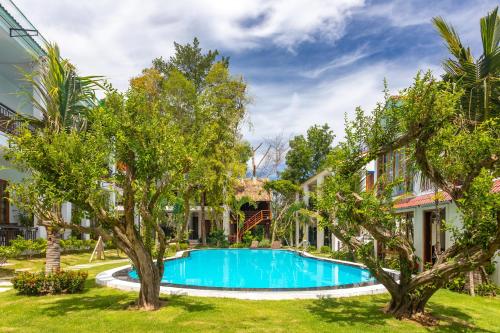 a swimming pool in a yard with trees at Casare Phu Quoc - Formerly Caesar Hotel in Phu Quoc