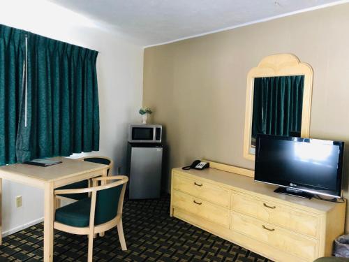 Habitación de hotel con TV y escritorio con mesa. en Motel Garberville en Garberville