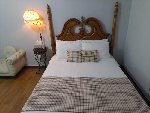 a bedroom with a bed with a wooden headboard and a chair at Charm Pension in Gapyeong