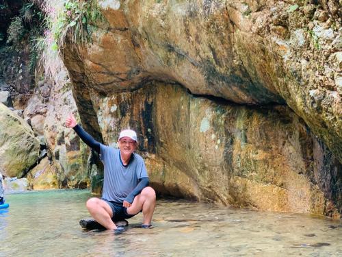a man kneeling in the water next to a rock formation at Leisure Courtyard Hotel Yangshuo in Yangshuo