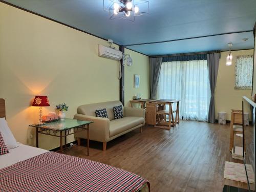 a room with a bed and a couch and a table at Charm Pension in Gapyeong
