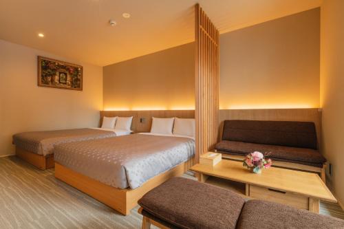 una habitación de hotel con dos camas y un sofá en GRAND BASE Fukuoka Tenjin, en Fukuoka