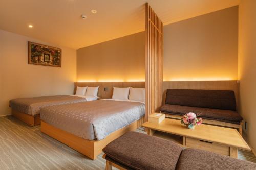 a hotel room with two beds and a couch at GRAND BASE Fukuoka Tenjin in Fukuoka