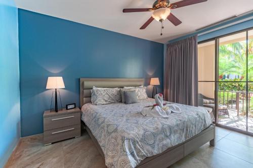 a blue bedroom with a bed and a ceiling fan at Nicely Decorated Ground-Floor Unit in Front of Pool at Pacifico in Coco in Coco