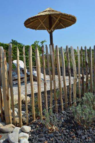 a wooden fence with an umbrella next to a bed at Relax B&B Lavendine Pure in Genk