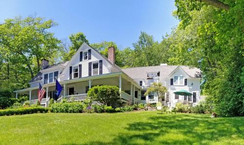 a large white house with an american flag at Timbercliffe Cottage Inn in Camden