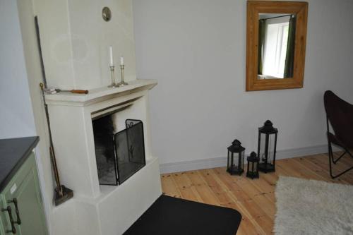 a living room with a fireplace and a mirror at Bli en del av Vråka by in Edsbruk