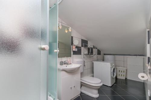 a white bathroom with a toilet and a sink at Apartments Mia in Omiš