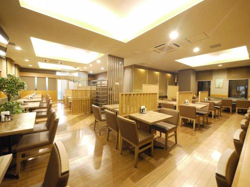 a restaurant with wooden tables and chairs and tables and chairs at Hotel Route-Inn Obihiro Ekimae in Obihiro