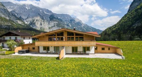 una casa in un campo con montagne sullo sfondo di Alpenchalet im Leutaschtal a Leutasch