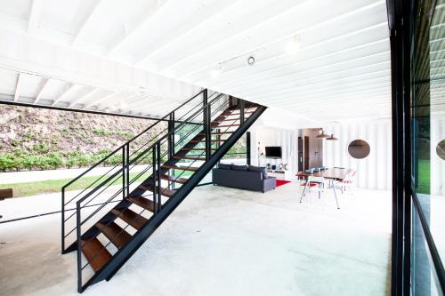 a glass staircase in a living room with a table at Bamboo Garden House in Laem Sing