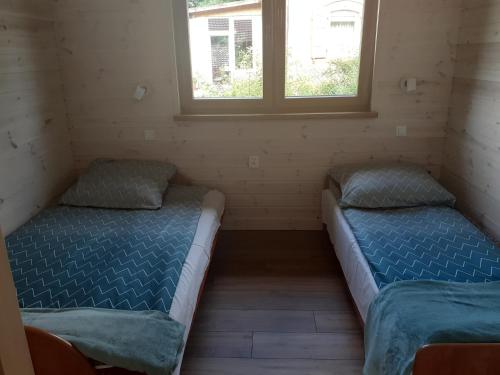 two beds in a room with two windows at Domki u Stasi in Stegna