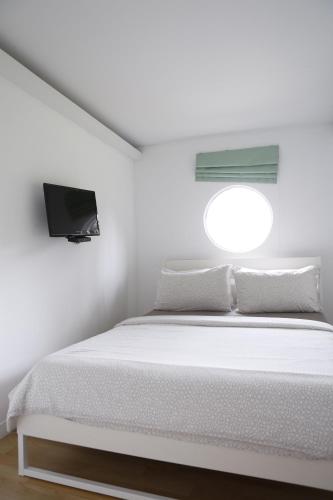 a white bedroom with a bed and a window at Bamboo Garden House in Laem Sing