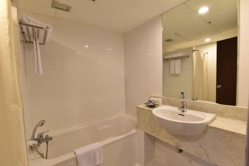 a white bathroom with a sink and a bath tub at Golden Crown Grand Hotel in Hat Yai