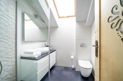 a white bathroom with a toilet and a sink at Apartamenty Bachledzki Wierch in Zakopane