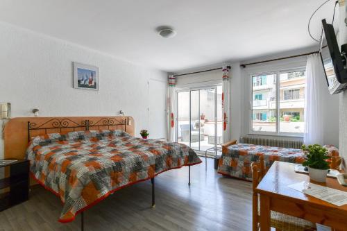 a bedroom with a bed and a table and windows at Le Preconil in Sainte-Maxime