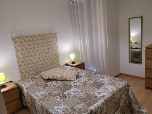 ein Schlafzimmer mit einem Bett, zwei Lampen und einem Spiegel in der Unterkunft Isis & Isa in Monte Gordo