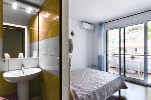 a bathroom with a sink and a bed and a window at Le Preconil in Sainte-Maxime