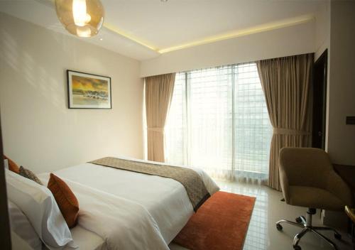 a bedroom with a bed and a window and a chair at Jatra Flagship Dhaka Lake View in Dhaka