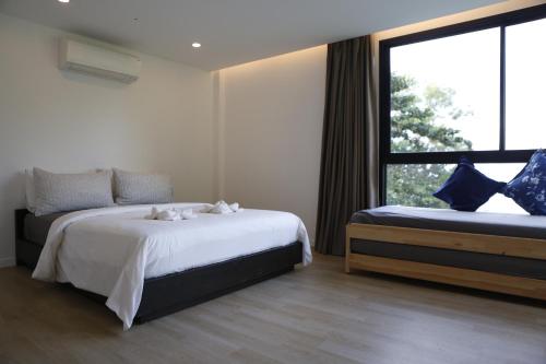 a bedroom with two beds and a large window at Bamboo Garden House in Laem Sing