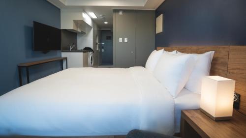a bedroom with a large white bed and a lamp at Marinabay Sokcho in Sokcho