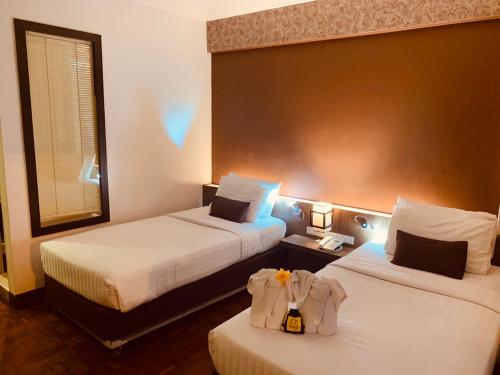 una camera d'albergo con due letti e uno specchio di Hotel M Chiang Mai a Chiang Mai