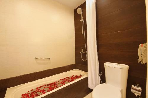 a bathroom with a toilet and a bath tub filled with roses at Fortune Select JP Cosmos, Bengaluru - Member ITC Hotels' Group in Bengaluru