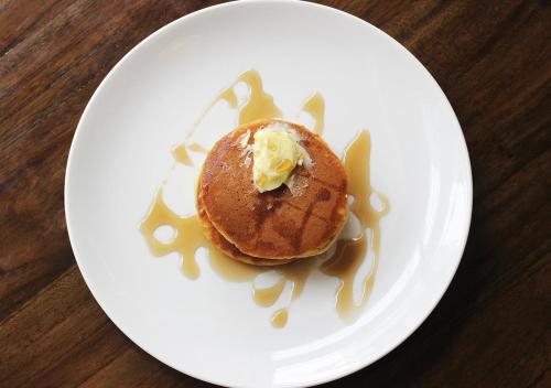 a white plate with a pancake with syrup on it at Jatra Flagship Dhaka Lake View in Dhaka