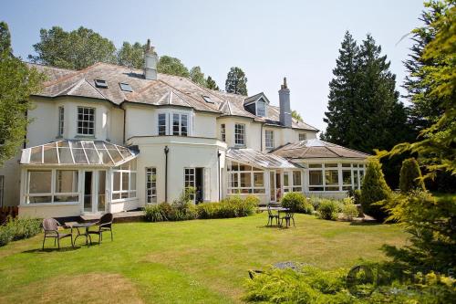 ein großes Haus mit einem Garten mit Stühlen in der Unterkunft Woodlands Lodge Hotel in Bartley