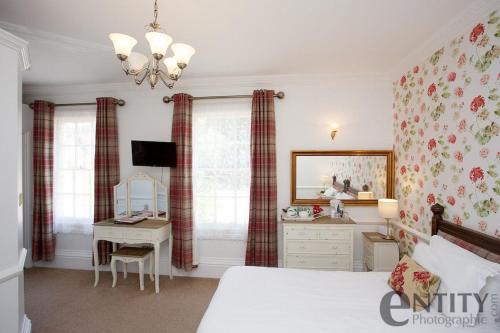 a bedroom with a bed and a desk and a mirror at Woodlands Lodge Hotel in Bartley