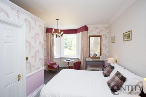 a bedroom with a bed and a table and a window at Woodlands Lodge Hotel in Bartley