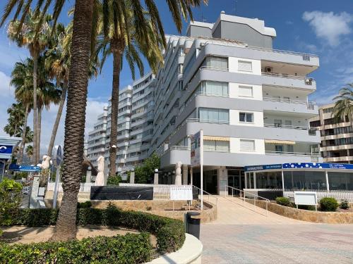 a large white building with palm trees in front of it at Service Apart Lazaro- Apartamentos Aguamarina 14 in Calpe