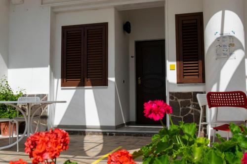 a front door of a house with red flowers at La Meriggia B&B in Pisciotta