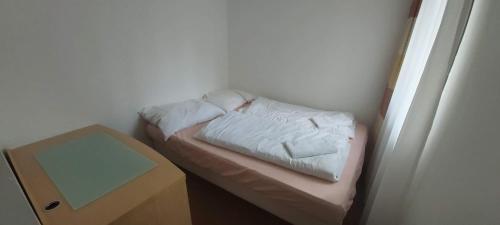 a small bed in a room with a table at Penzion Sykovec in Tři Studně